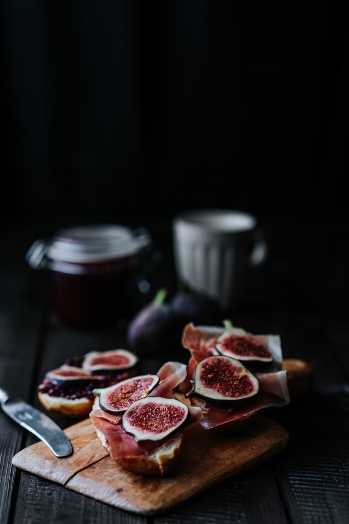 Bread with ham and fresh  figs served on a wooden plate on dark background